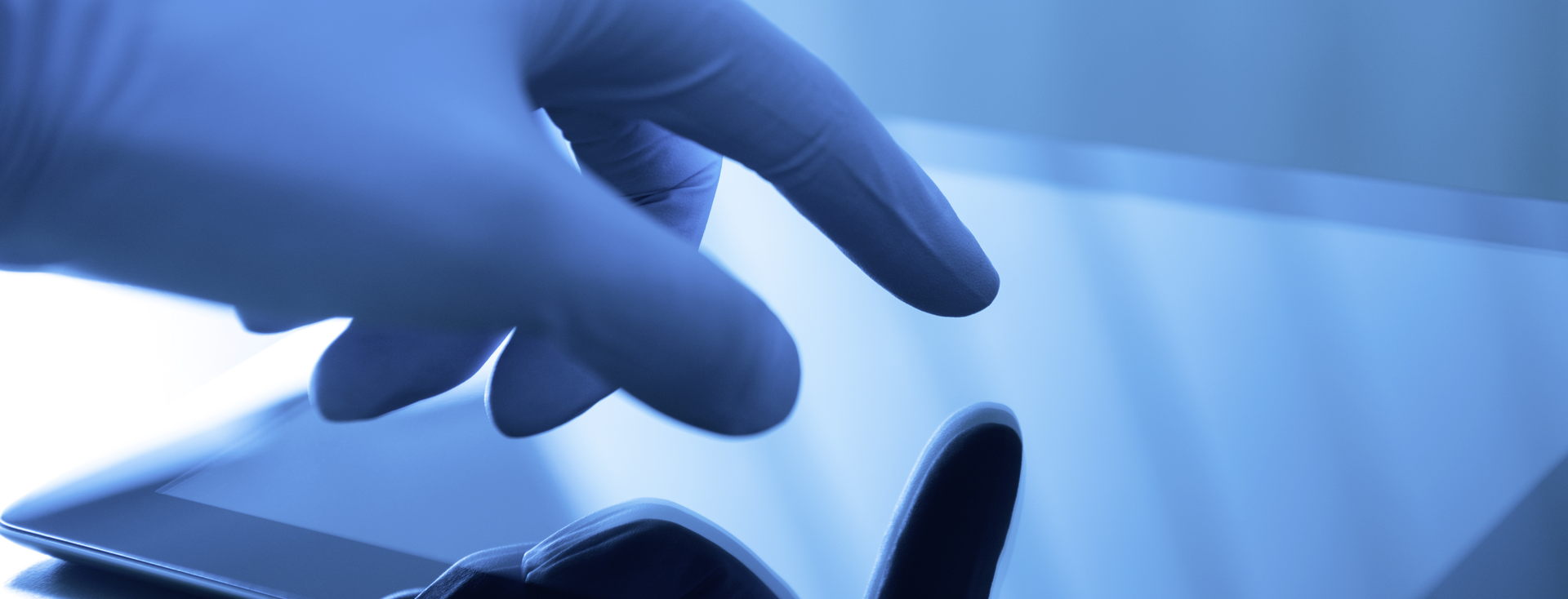 Hand in einem Latexhandschuh bedient einen Touchscreen