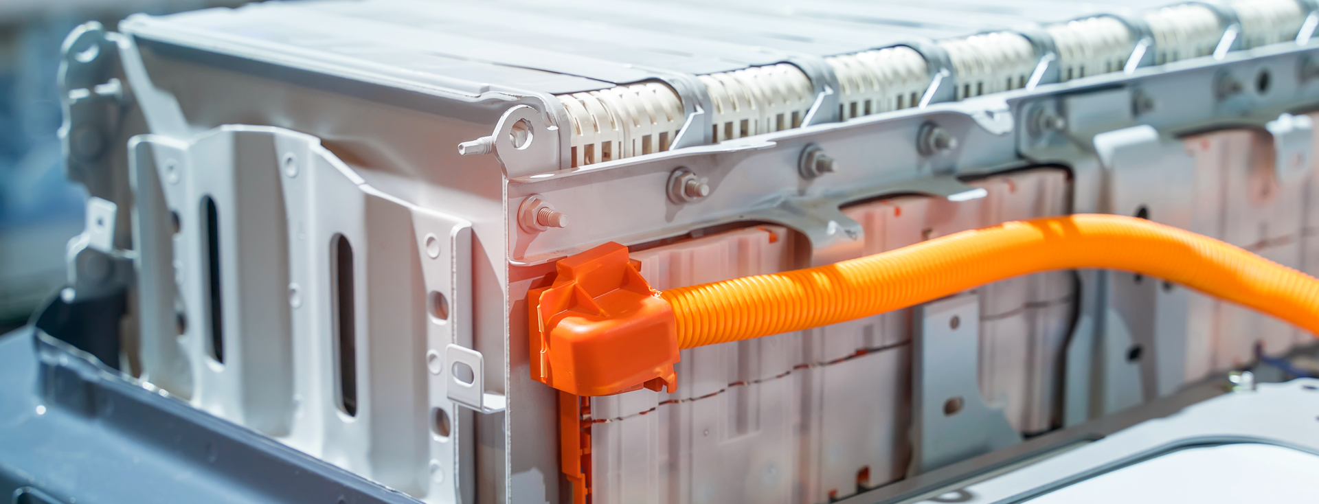 Detailansicht eines großen Lithium-Ionen-Akkupacks eines Elektrofahrzeugs mit orangefarbenem Kabel